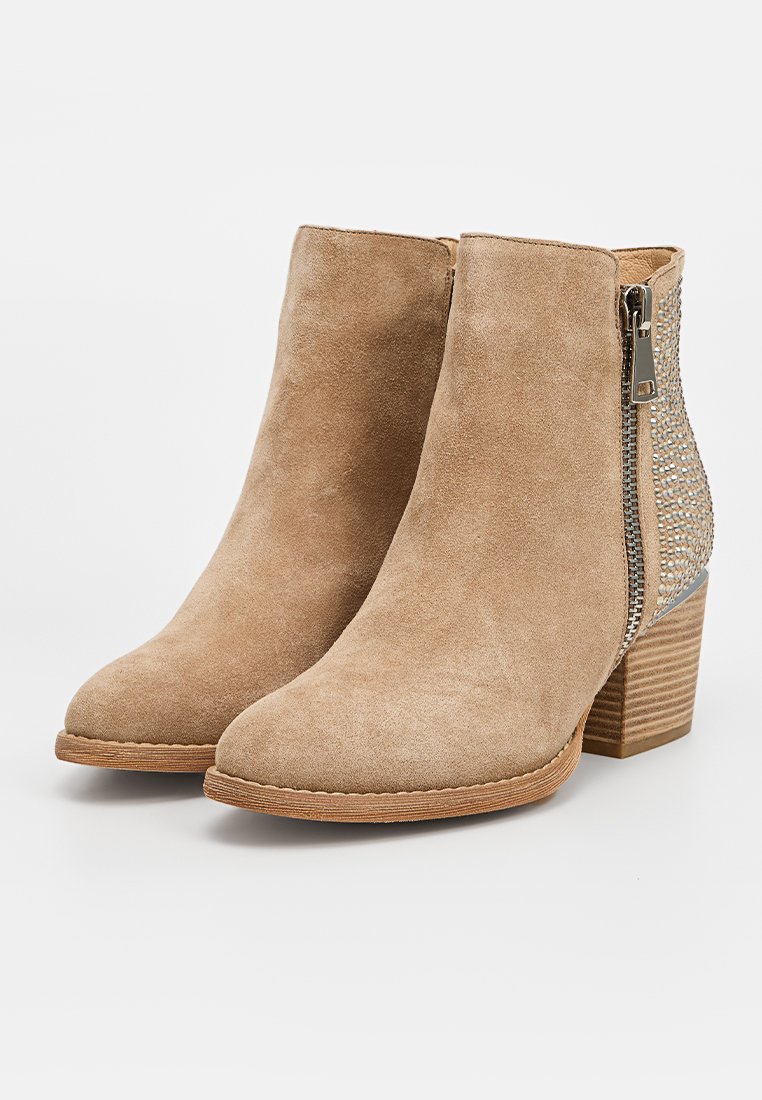 Botines de ante beige con un panel lateral texturizado, cierre de cremallera plateada y un tacón de madera. Cuenta con un diseño de punta redondeada.