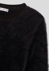 Czarny sweter z miękkim, teksturowanym wykończeniem i prążkowanym dekoltem. Tkanina wygląda na miękką i puszystą, co zwiększa ciepło i komfort.