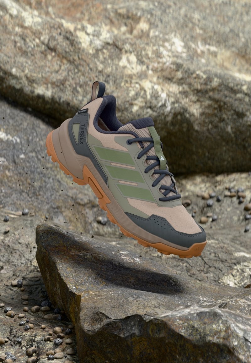 Ελαφρύ πεζοπορικό παπούτσι με μπεζ και ελιά συνθετικό επάνω μέρος, γκρι λεπτομέρειες και υφασμένο λαστιχένιο πέλμα για πρόσφυση.