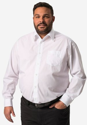 Witte blouse met lange mouwen en knopen, voorzien van een klassieke kraag, één borstzak en manchetten, gecombineerd met donkere broek en een zwarte riem.
