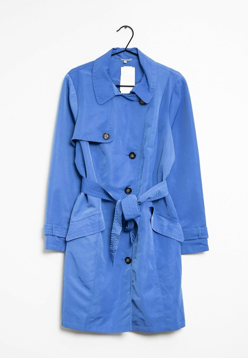 Blå knälång trenchcoat med knappar, bälte vid midjan, fickor med luckor och bred krage, hängande på en svart galge mot en vit bakgrund.