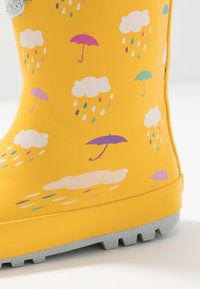 Żółte gumowe kalosze z teksturowaną szaro-skalą. Ozdobione białymi chmurkami oraz kolorowymi parasolkami w różowym, niebieskim i purpurowym kolorze.