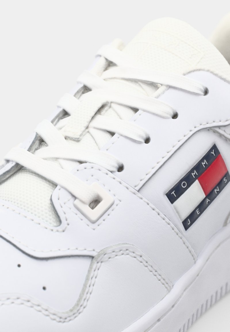 Sneaker in pelle bianca con pannello in rete, lacci tondi e etichetta del logo in rosso, bianco e blu. Suola testurizzata con dettagli di cucitura.