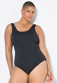 Maillot de bain une pièce noir avec un décolleté plongeant, présentant un matériau texturé qui brille. Bretelles arrondies et découpes hautes au niveau des jambes.