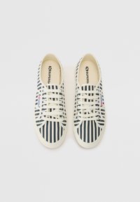 Canvas sneakers featuring a navy and white vertical stripe pattern, round toes, and a textured rubber sole with white laces.