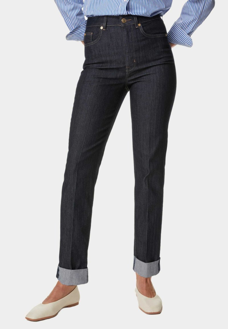 Jeans de mezclilla oscuros de tiro alto con un corte recto, dobladillos acampanados y detalles en dorado. Material de algodón con un ligero estiramiento.