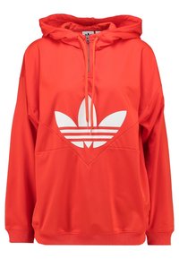 Red hooded sweatshirt with a half-zip front. Features a large white Adidas logo and textured accent panel at the chest. Long sleeves with ribbed cuffs.