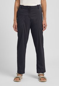 Dunkelmarineblaue, leichte Hose mit glatter Oberfläche, ausgestattet mit Fronttaschen und einem Knopfverschluss am Bund. Kombination mit beigen Sandalen.