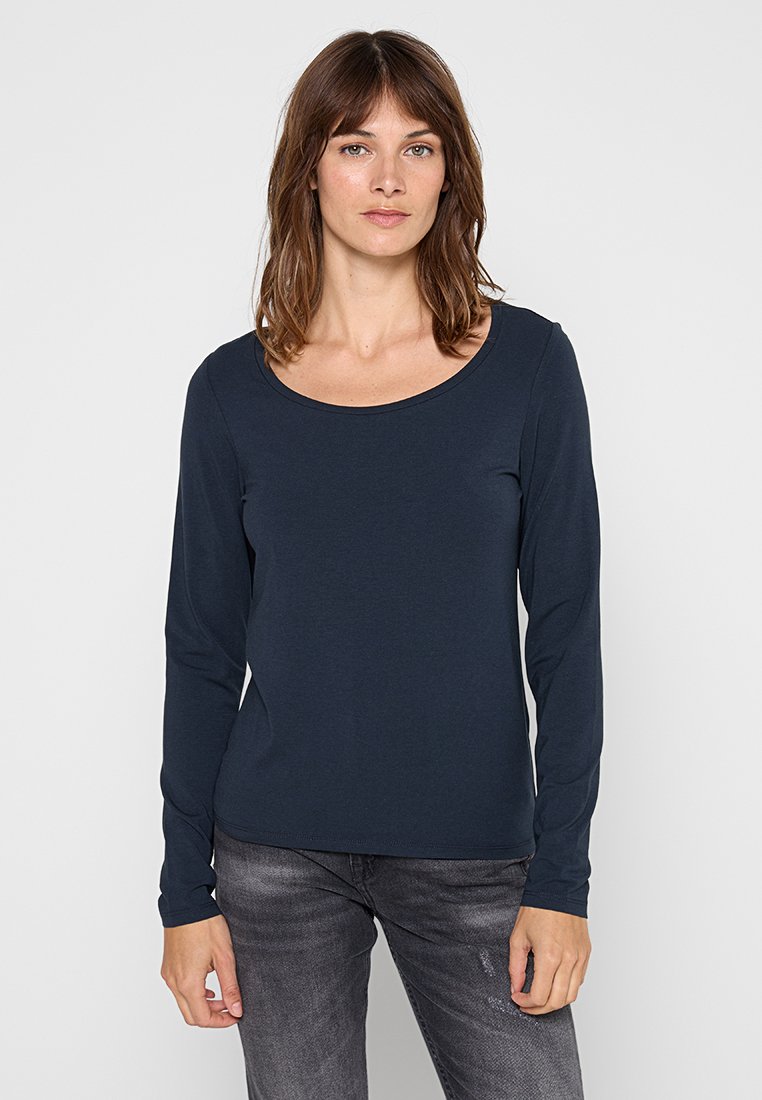 Granatowa koszula z długim rękawem z miękkiego materiału z okrągłym dekoltem, w zestawie z jasnoszarymi dżinsami. Gładka tekstura o klasycznym kroju.