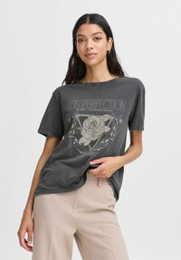 Mørk grå T-shirt med korte ærmer, der har et grafisk design af en rose og tekst. Stoffet ser blødt og let struktureret ud.
