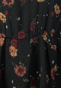 Robe en tissu noir avec un motif floral, présentant des fleurs rouges, orange et blanches. Surface texturée avec un détail de taille froncée.