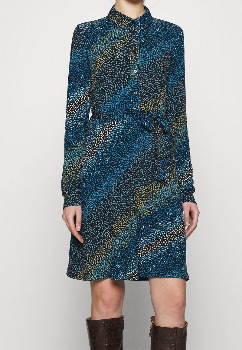 Langärmliges Hemdkleid in einem blauen, schwarzen und goldenen abstrakten Muster, mit tailliertem Schnitt und glatter Stoffstruktur.