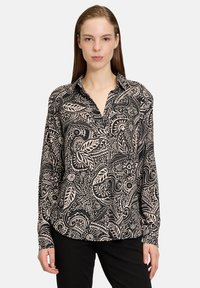 Zwarte en beige lange mouwen shirt met een ingewikkeld bloem- en abstract patroon, met een kraag en een relaxte pasvorm.