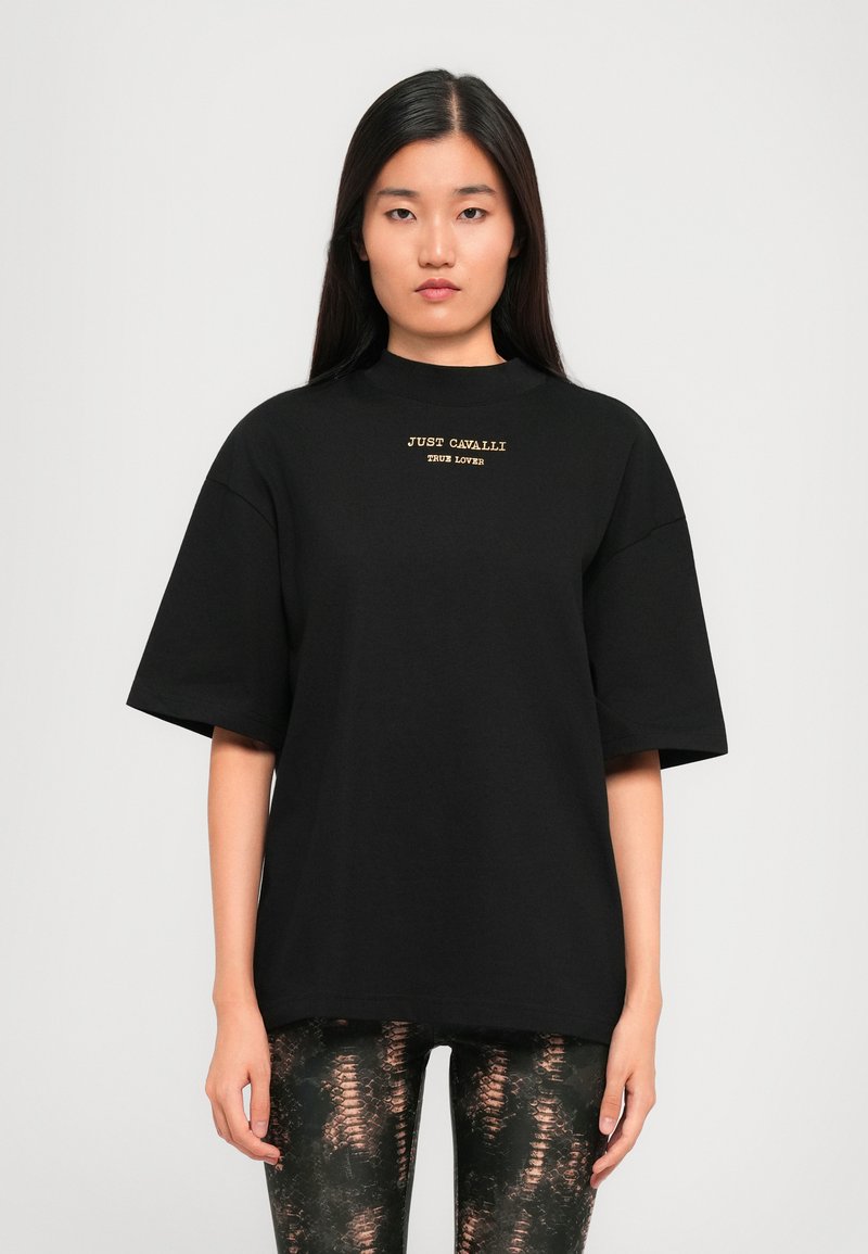 T-shirt nera oversize con maniche corte, caratterizzata da ricami dorati che recitano "JUST CAVALLI TRUE LOVER" sul petto.