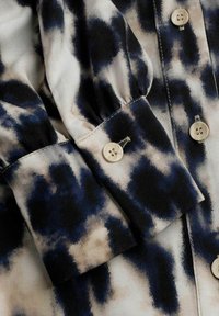 Katoenen shirt in een tie-dye patroon met donkerblauwe, crème en zwarte tinten. Knopenmanchetten met een gestructureerde afwerking en ronde knopen.