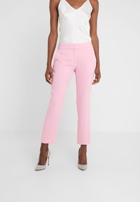 Rosa skräddarsydda byxor med smal passform, slät textur och medelhög midja, tillsammans med en vit siden camisole och silverfärgade klackar.