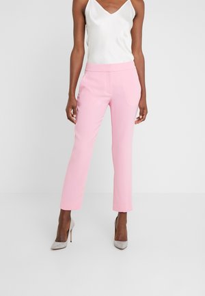 Roze op maat gemaakte broek met een slanke pasvorm, een soepel textuur en een middelhoge taille, gecombineerd met een witte zijden cami-top en zilveren hoge hakken.