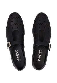 Schwarze Schuhe mit ausgeschnittenen dreieckigen und kreisförmigen Mustern, im Mary-Jane-Stil, mit einem Schnallenriemen und strukturiertem Innenfutter.