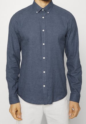 Ciemnoniebieska koszula z długim rękawem, zapinana na guziki, w kratkę, z standardowym kołnierzykiem. Tekstura materiału wydaje się miękka i gładka.