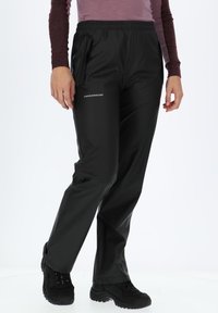 Pantaloni impermeabili neri con vita elasticizzata, tasche laterali e logo frontale. Il materiale sembra liscio e lucido.