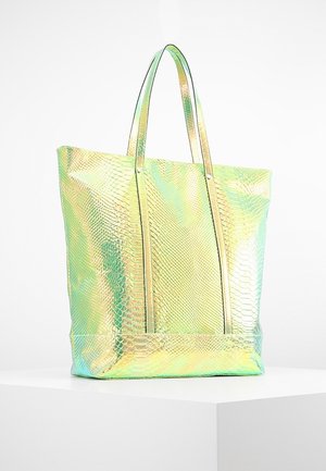 Tote bag met iriserende goud-groene slangenhuidstructuur, twee lange hengsels, rechthoekige basis, rechtopstaand op een wit voetstuk.