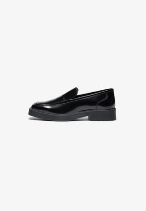 Black leather slip-on shoes with a rounded toe and a low, chunky rubber sole. Smooth texture with minimal stitching details.