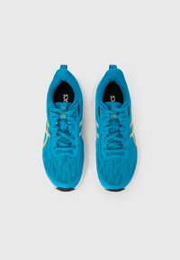 Blauwe sportschoenen met een ademend mesh bovenwerk, een gestructureerd patroon, een witte tussenzool en subtiele gele en grijze accenten. Veilig vetersysteem.