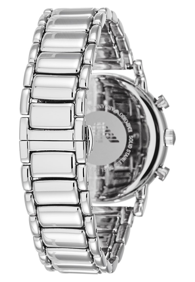 Reloj de pulsera de acero inoxidable plateado con una pulsera de eslabones rectangulares pulidos y una tapa trasera transparente que muestra el mecanismo interno.