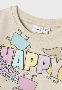 Bežna majica s rebrastim izrezom, ki ima napis "HAPPY" v barvitih, bleščečih črkah in pisane ilustracije karakterjev.
