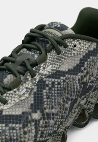 Tenisky s tmavě zelenými tkaničkami a svrchním materiálem s texturou hadí kůže, vybavené tvarovanou podrážkou s odpružením a detaily vzduchové kapsy.