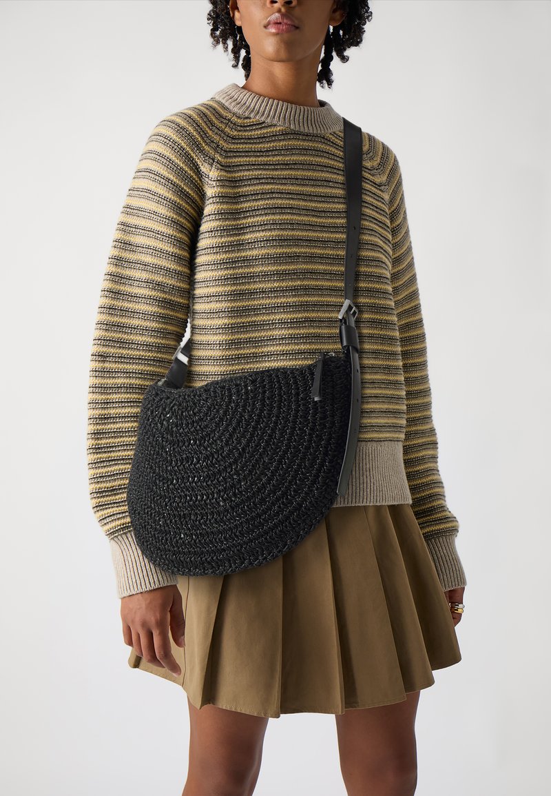 Borsa a tracolla nera intrecciata con una forma curva a mezzaluna, dotata di una tracolla in pelle e una superficie texturizzata.