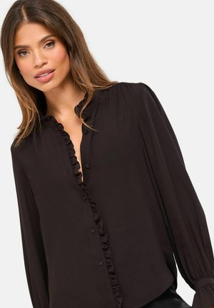 Musta pusero, jossa on rypytetty kaulus ja etuaukko, pitkät hihat ja silkkinen pinta. Keskellä on napit rivissä.