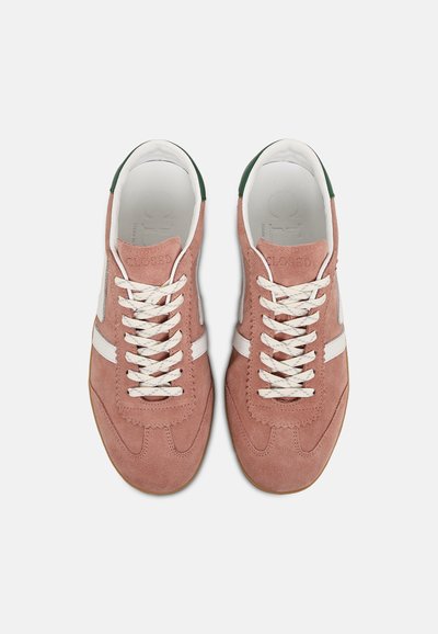 Paire de baskets en daim rose avec lacets blancs et bandes, accents verts au talon, vue de dessus sur un fond clair.