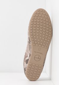 Semelle d'une chaussure à motif serpent avec une semelle extérieure en caoutchouc beige comportant des crampons rectangulaires et le nom de la marque "Tamaris" en taille 37.
