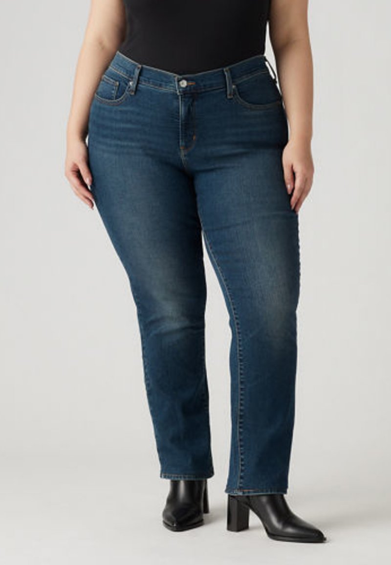 Tamsiai mėlyni lieso silueto džinsai, vidutinio aukščio liemeniu, tradiciniu penkių kišenių dizainu ir subtiliomis išblukimo detalėmis, derinami su juodais aukštakulniais batais.