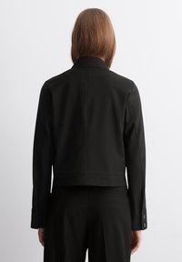 Zwart getailleerd jack met lange mouwen, kraag en knoopmanchetten. Glad materiaal, cropped ontwerp en subtiele naaddetails aan de achterkant.