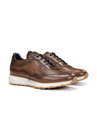 Zapatillas de cuero marrón con un acabado texturizado, que presentan un bordado intrincado, punta redondeada y una suela de goma blanca con acentos marrones.
