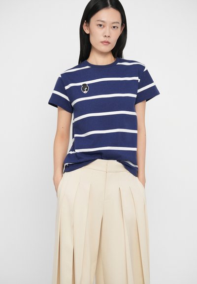 Ναυτικό καρό μπλουζάκι με λευκές οριζόντιες ρίγες, στρογγυλή λαιμόκοψη και κοντά μανίκια. Διαθέτει κεντητή γραφική παράσταση στο στήθος.