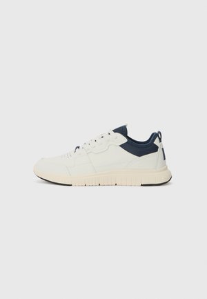 Sneakers featuring a white synthetic upper, navy fabric accents, textured sole, and lace-up closure. Rounded toe and back pull tab.