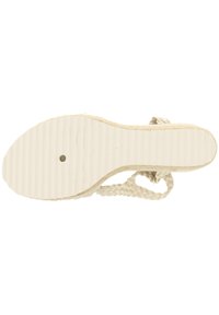 Bijela espadrila sandal s potplatom s teksturiranim žljebovima, pletenim detaljima na remenu i ravnom, fleksibilnom bazom za udobnost.