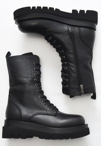 Černé kožené vojenské boty s šněrováním v přední části, bočním zipem a chunky gumovou podrážkou s rýhovaným vzorem.