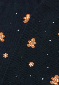 Marineblaue Socken mit strukturierter Oberfläche, verziert mit einem orangefarbenen Lebkuchenmann- und Schneeflockendesign, akzentuiert durch weiße Punkte für zusätzliche Details.