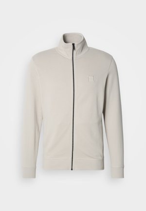 Light grey zip-up jacket made of soft fabric. Features a high collar, long sleeves, and subtle logo detail on the chest.