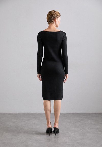 Black fitted long-sleeve dress with a square neckline, ribbed texture, knee-length, paired with black high-heeled shoes.