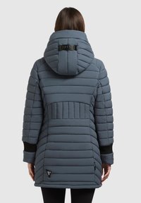 Šedý puffer kabát s horizontálne prešívanými panelmi, veľkou kapucňou, rebrovanými manžetami a štítkom s logom blízko lemu. Hladká textura a neformálny dizajn.