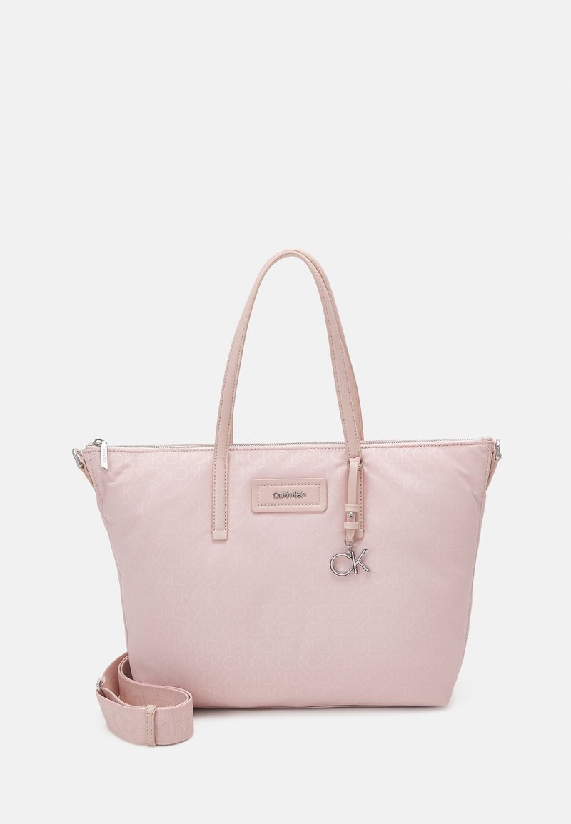 Sac fourre-tout rose en nylon lisse, doté de doubles poignées, d'une bandoulière amovible et d'un charm logo CK argenté. Orné d'un motif à branding subtil.