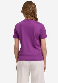 Paarse katoenen t-shirt met korte mouwen en een ronde hals, met een zachte textuur en een ontspannen pasvorm. Zichtbare naden op de schouders.