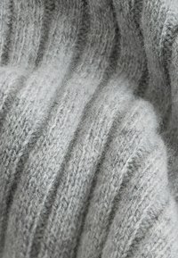 Gray knitted fabric with visible ribbed texture, featuring soft, fuzzy fibers and a uniform color. No distinct patterns or hardware.