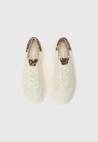 Sneaker bianche in pelle con lacci crema e un accento maculato sul collo. Suola piatta, design a punta rotonda. La fodera interna include il testo del marchio.