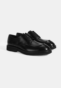 Schwarze Lederschuhe mit glatter Oberfläche, runder Zehenform und Schnürdesign. Dicke Sohle mit sichtbaren Nähten.